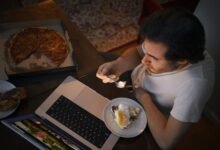 A man enjoying his takeaway food while working during night